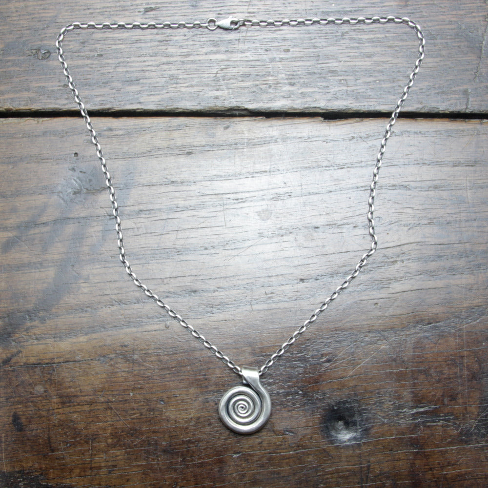 Flat lay of a Wrought Silver Spiral Necklace Taitaya Forge