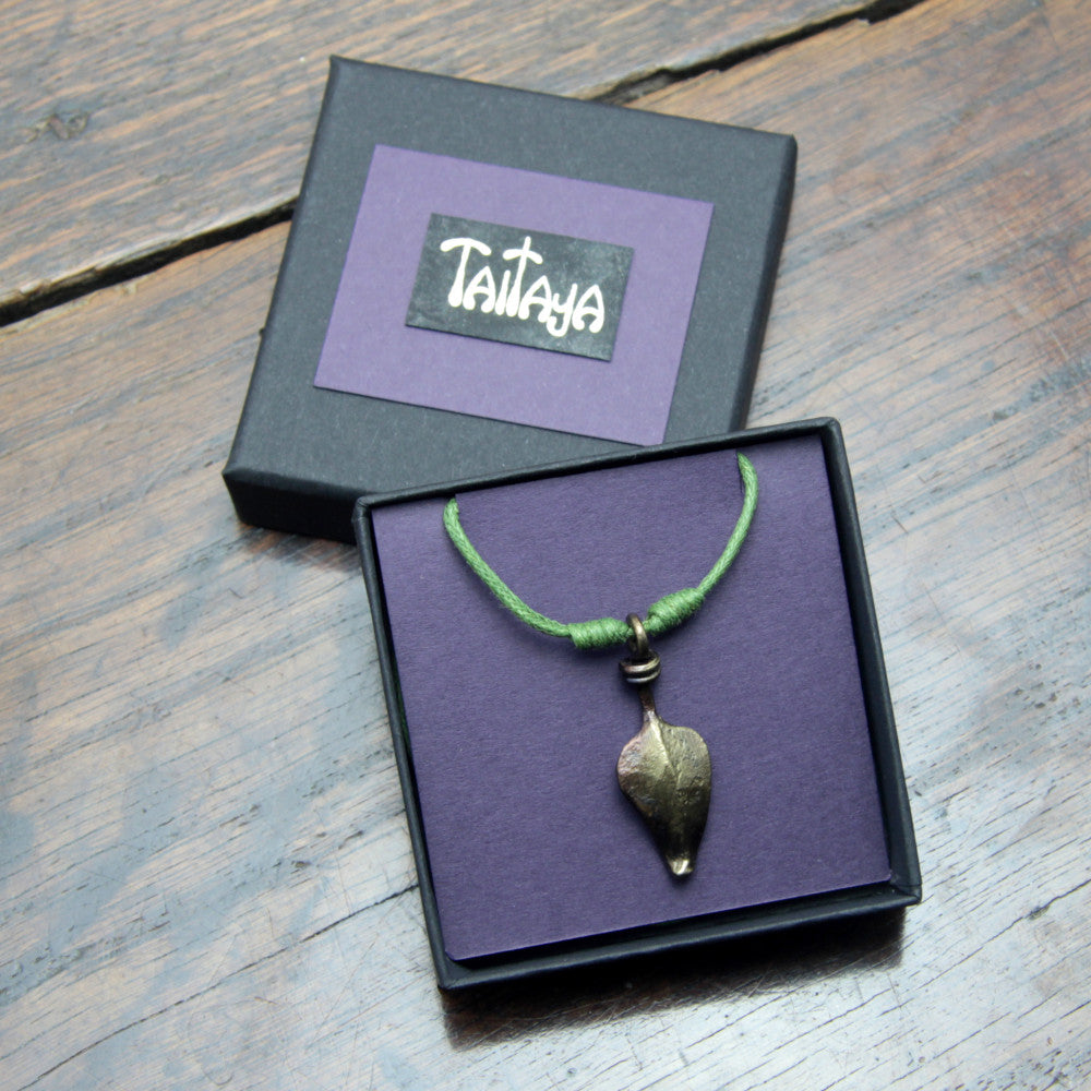 Taitay Forge iron leaf pendant presented in a black gift box with gold embossed logo and a purple card insert.