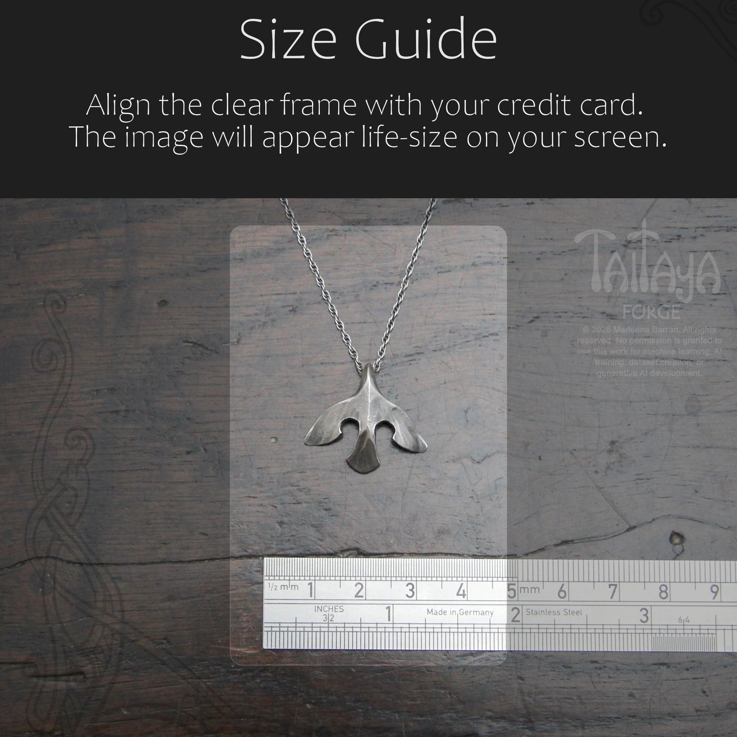 Silver raven pendant necklace displayed on a clear measurement card over a dark wood background, with a ruler at the bottom and a black header reading 'Size Guide' and instructions about aligning the frame with a credit card.