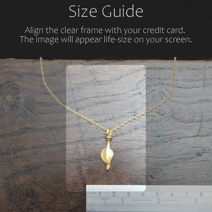 Gold necklace with a clear frame for size guide on a wooden surface