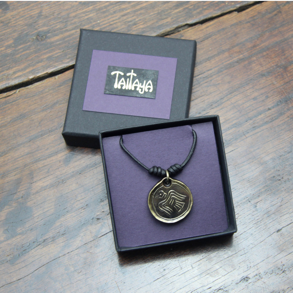 Taitay Forge Iron Viking Raven coin pendant with antique bronze finish presented in a black gift box with gold embossed logo and a purple card insert. 