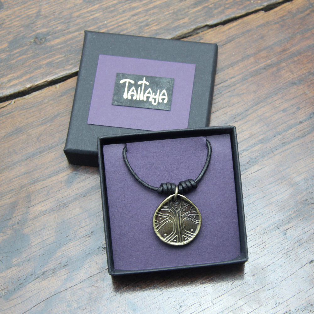 Taitay Forge Iron Yggdrasil tree coin pendant with antique bronze finish presented in a black gift box with gold embossed logo and a purple card insert. 