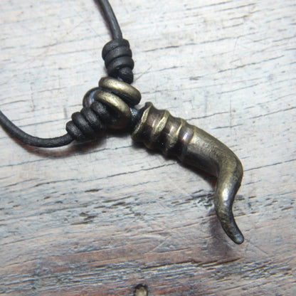 A forged iron cornicello, Italian horn, pendant with a antique bronze finish, on a black leather cord, designed and made by M Barran at Taitaya Forge.  View of the back of the pendant.