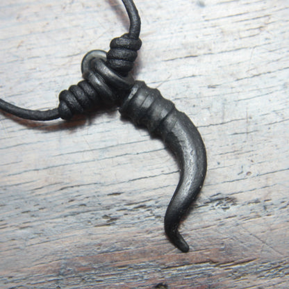 A forged iron cornicello, Italian horn, pendant with a black finish, on a black leather cord, designed and made by M Barran at Taitaya Forge.  Back of the pendant