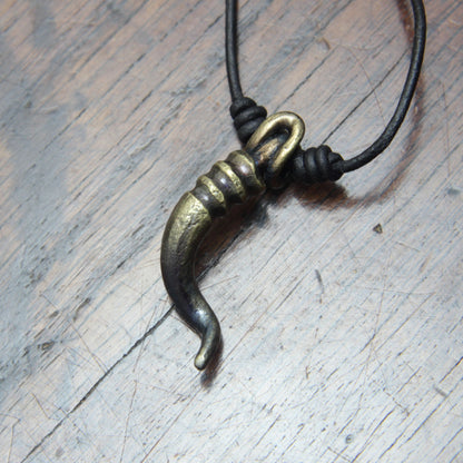 A forged iron cornicello, Italian horn, pendant with a antique bronze finish, on a black leather cord, designed and made by M Barran at Taitaya Forge. 