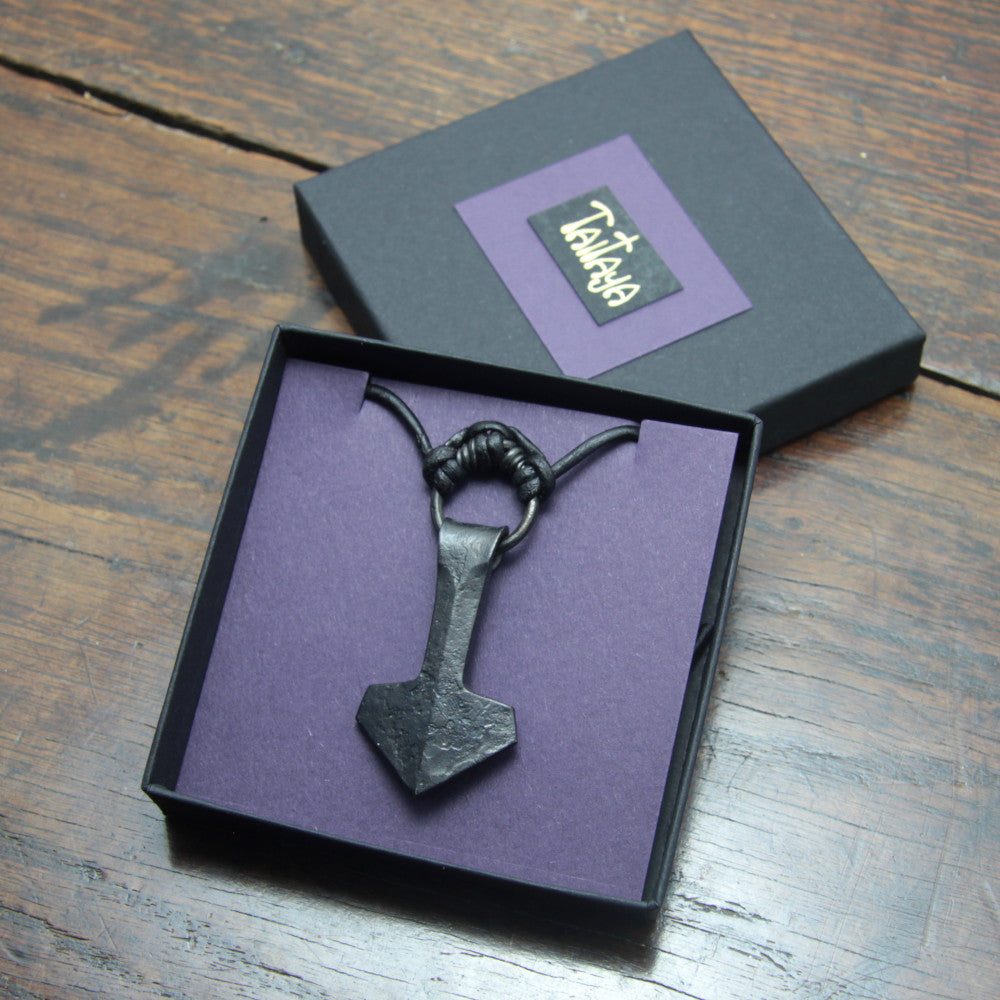 Handforged large ringed iron Mjolnir Thor's hammer pendant made by taitaya forge, presented in a black card gift box with gold embossed branding and purple insert card. 