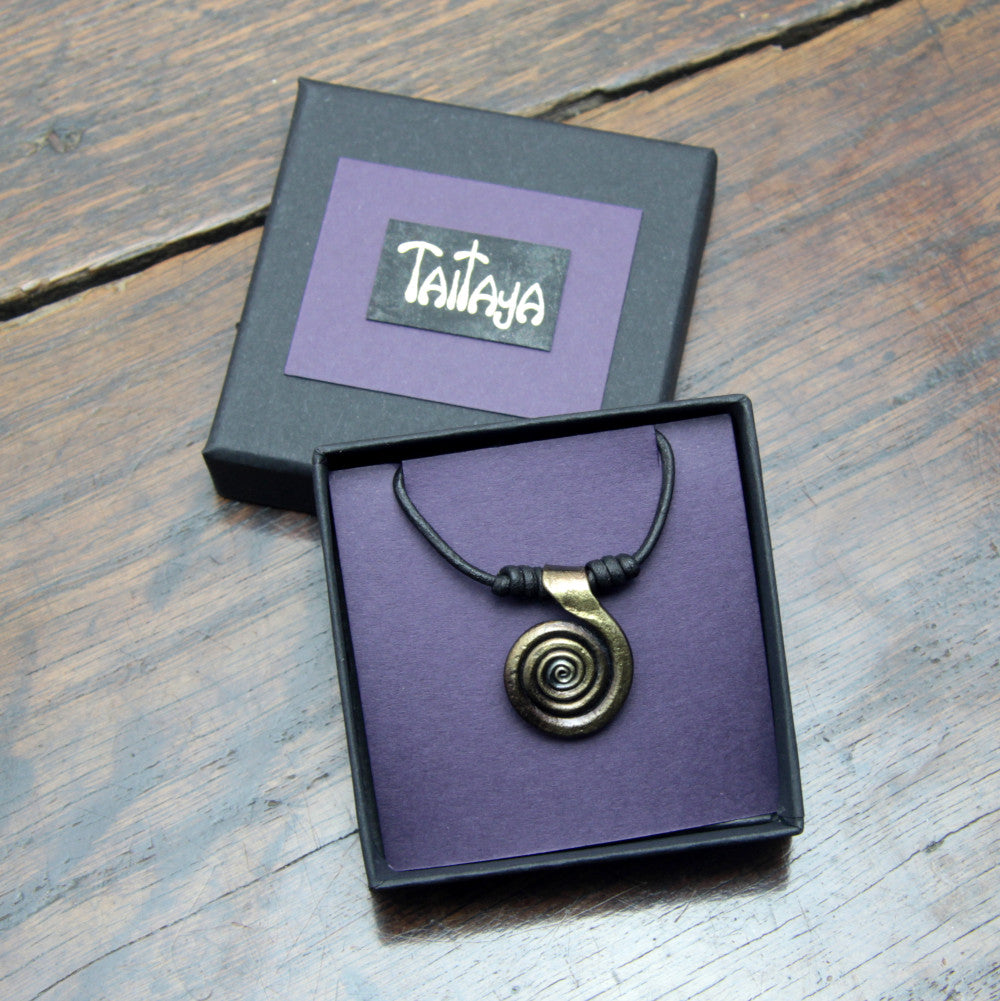 Taitay Forge iron spiral pendant presented in a black gift box with gold embossed logo and a purple card insert. 