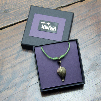 Taitay Forge iron leaf pendant presented in a black gift box with gold embossed logo and a purple card insert. 