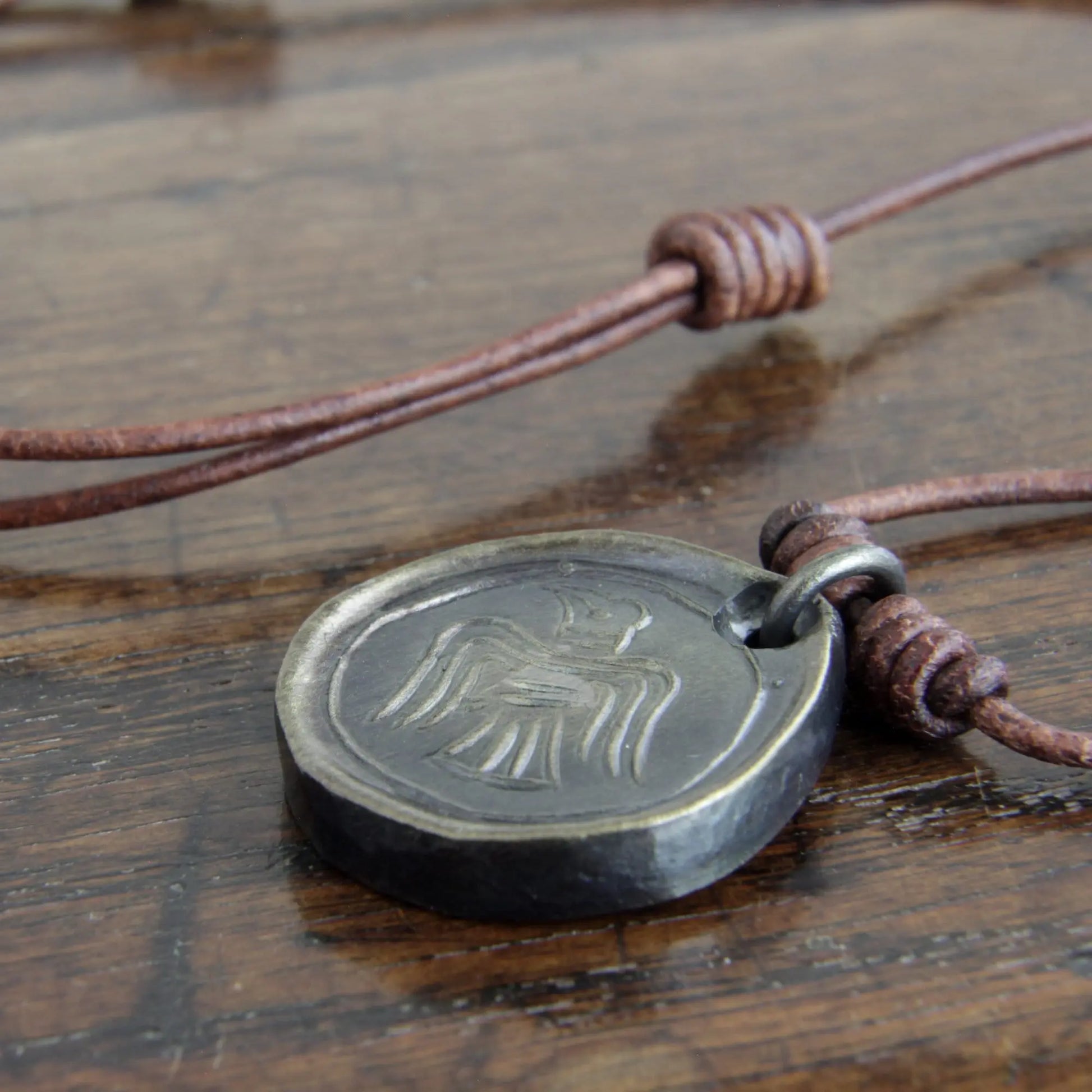 The side view showing the thickness and adjustable knots in the leather of the Viking Raven Iron Coin Necklace. Norse Raven medallion pendant that can be personalised with silver inlay or a personal engraving.