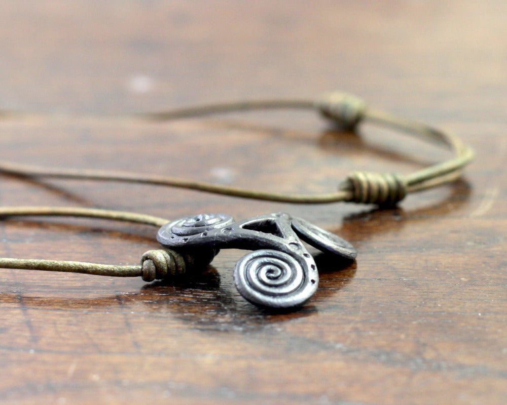 Side view of  a Hand Forged Iron Triskelion Necklace, designed and made by Blacksmith Marleena Barran from Taitaya Forge