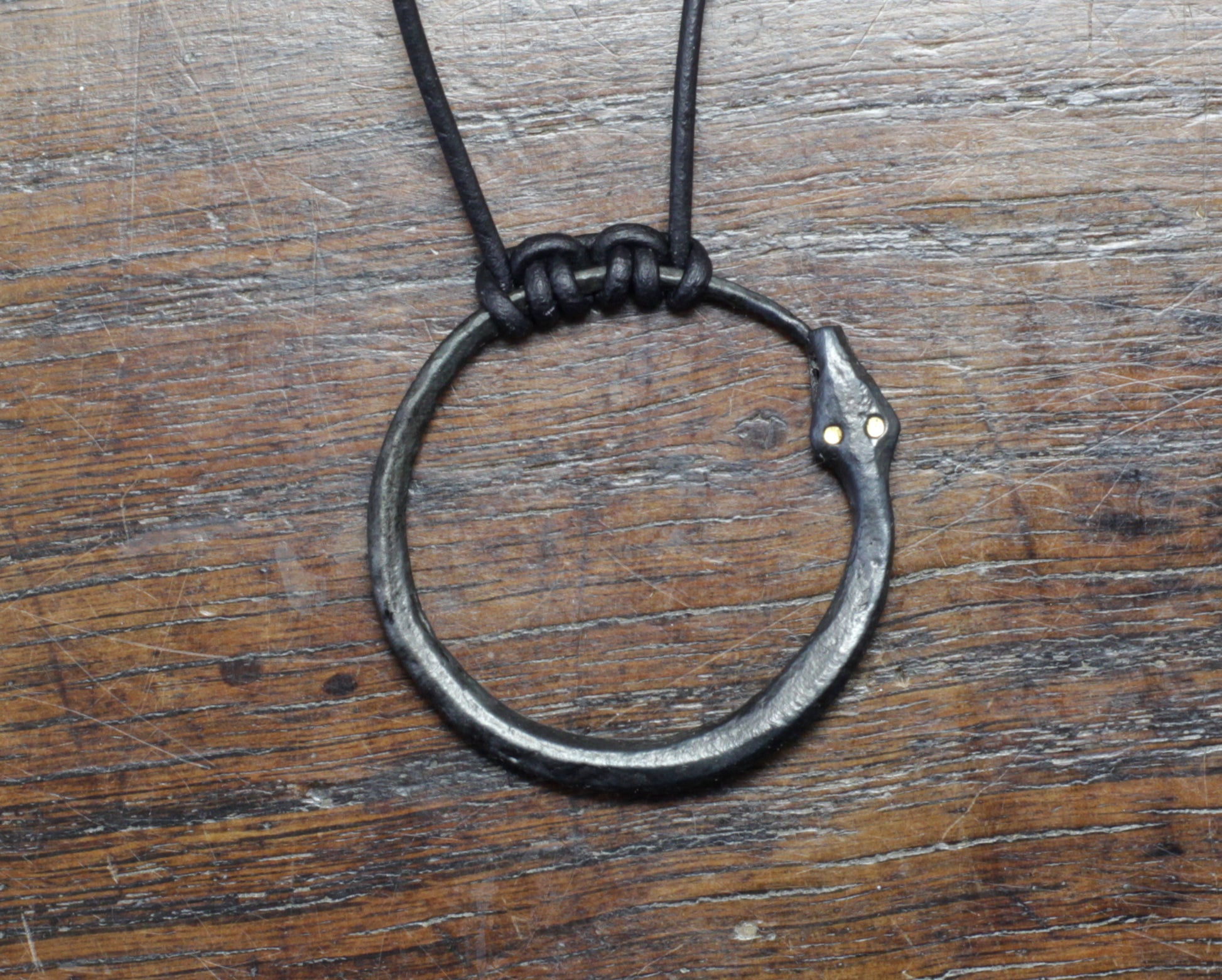 Hand forged Pure iron Ourboros with solid gold eyes. Pendant on a leather cord, made and designed by M.Barran Taitaya Forge, UK